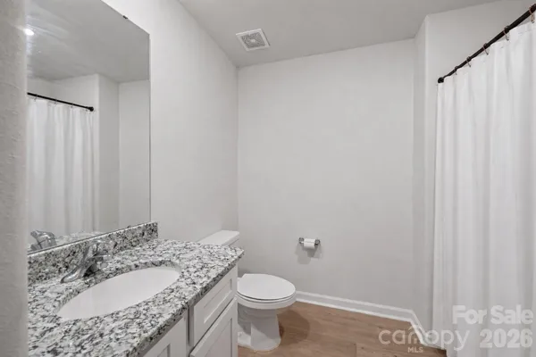 a bathroom with a granite countertop sink toilet and a mirror