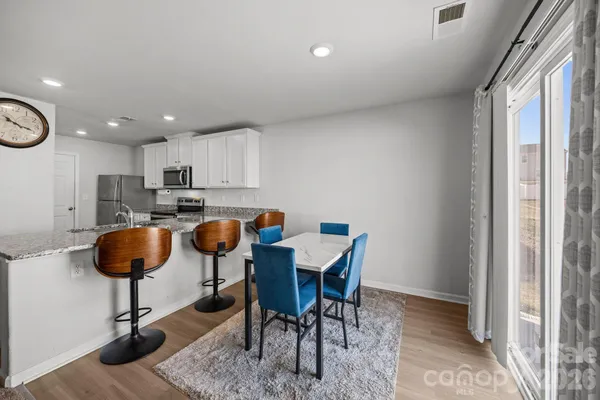 a kitchen with stainless steel appliances granite countertop a dining table chairs and a refrigerator