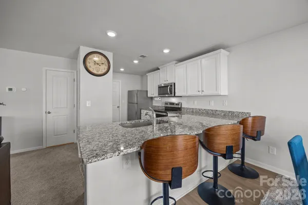 a kitchen with granite countertop a table chairs stove and cabinets