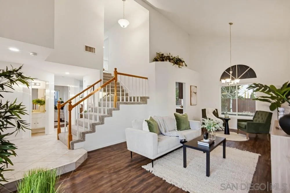 39900 Quigley Road Murrieta, CA 92562 - Photo 22 of 58 a living room with couches chandelier and a dining table with wooden floor