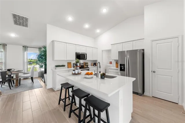 a kitchen with stainless steel appliances a dining table chairs refrigerator and microwave