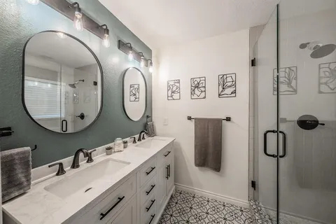a bathroom with a double vanity sink mirror and tub