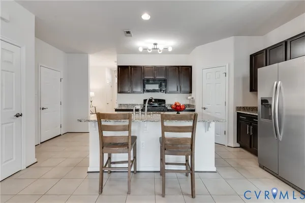 a kitchen with granite countertop a refrigerator and a stove top oven