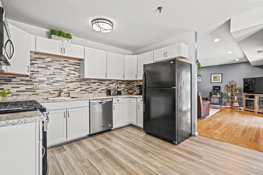 124 Tennis Plaza Road, Unit 21 Dracut, MA 01826 - Photo 13 of 27 a kitchen with stainless steel appliances granite countertop a refrigerator and a stove top oven
