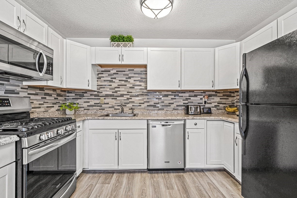 124 Tennis Plaza Road, Unit 21 Dracut, MA 01826 - Photo 14 of 27 a kitchen with stainless steel appliances a sink stove and refrigerator