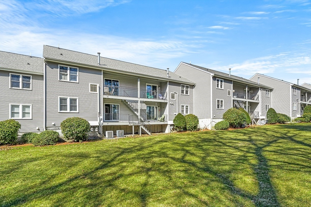 124 Tennis Plaza Road, Unit 21 Dracut, MA 01826 - Photo 26 of 27 a front view of a house with a garden