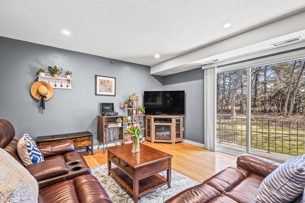 124 Tennis Plaza Road, Unit 21 Dracut, MA 01826 - Photo 6 of 27 a living room with furniture a flat screen tv and a large window