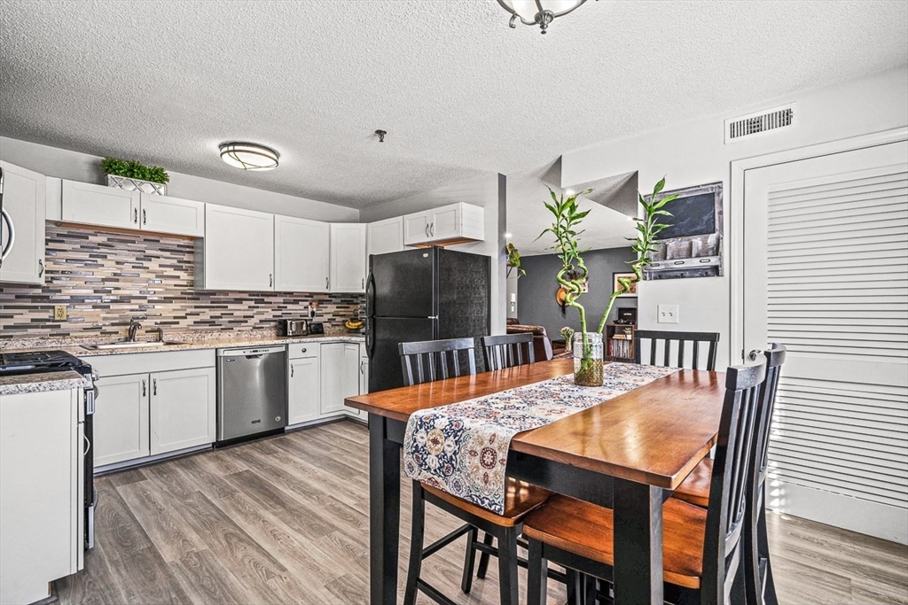 124 Tennis Plaza Road, Unit 21 Dracut, MA 01826 - Photo 9 of 27 a kitchen with granite countertop white cabinets and stainless steel appliances