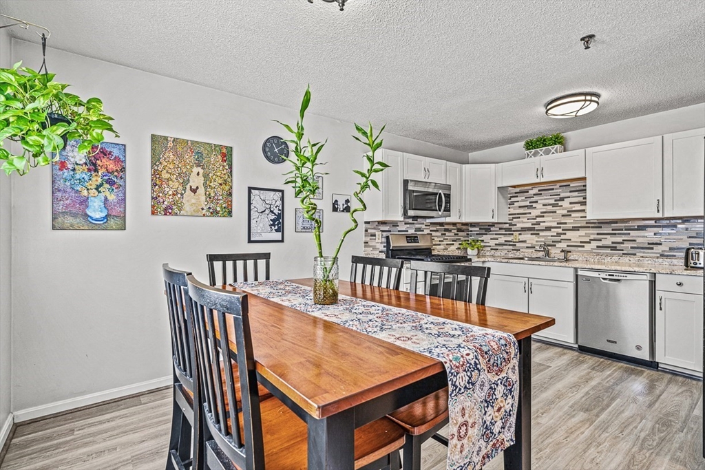 124 Tennis Plaza Road, Unit 21 Dracut, MA 01826 - Photo 10 of 27 a kitchen with granite countertop a stove a sink a dining table and chairs