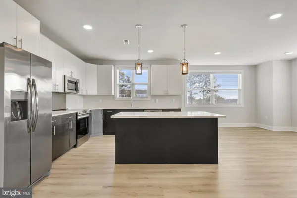 a kitchen with stainless steel appliances granite countertop a refrigerator a sink a stove and a wooden floors
