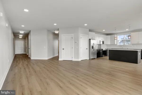 a view of kitchen with kitchen island wooden floor center island and stainless steel appliances
