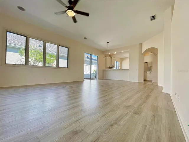 an empty room with wooden floor and a ceiling fan