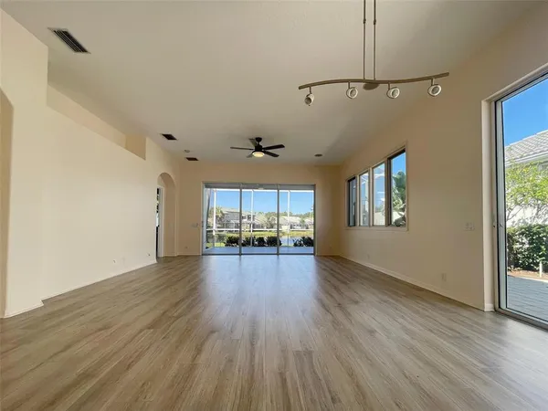 an empty room with wooden floor and a ceiling fan
