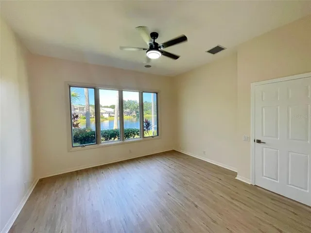 a view of a room with wooden floor and a ceiling fan