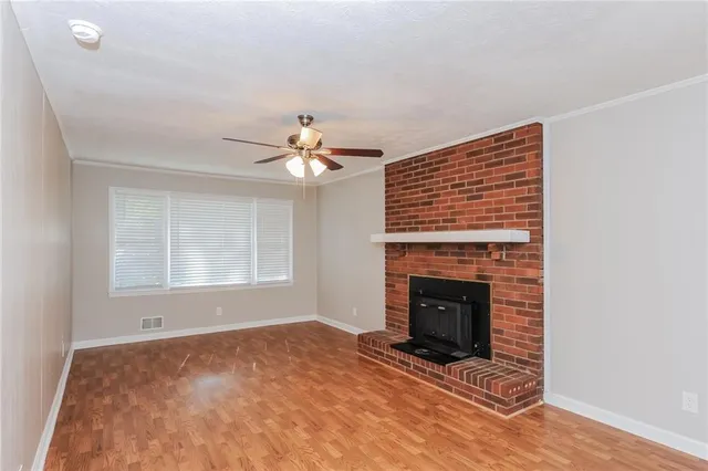 a view of an empty room with chandelier fan and fire place