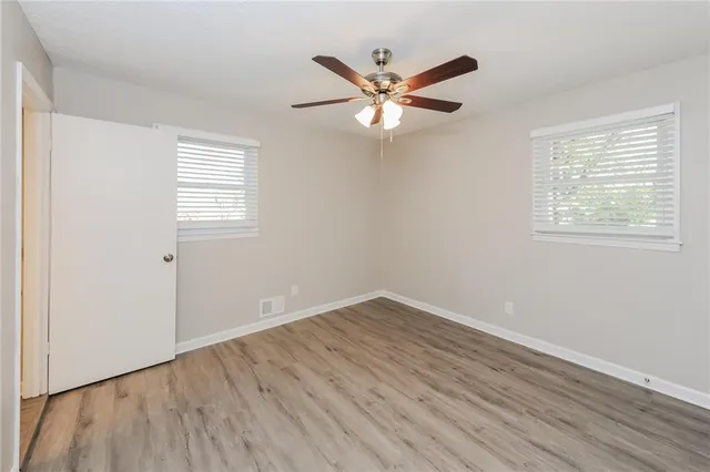 a view of a big room with wooden floor and windows