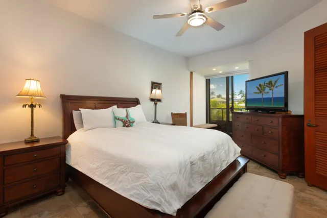 a bedroom with a bed and a flat tv screen on dresser