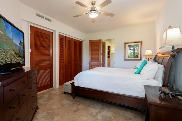 a spacious bedroom with a bed and a flat screen tv