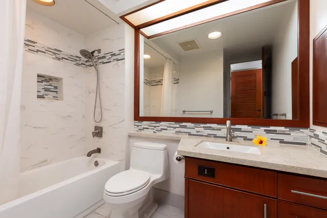 a bathroom with a sink a toilet a mirror a bathtub and shower