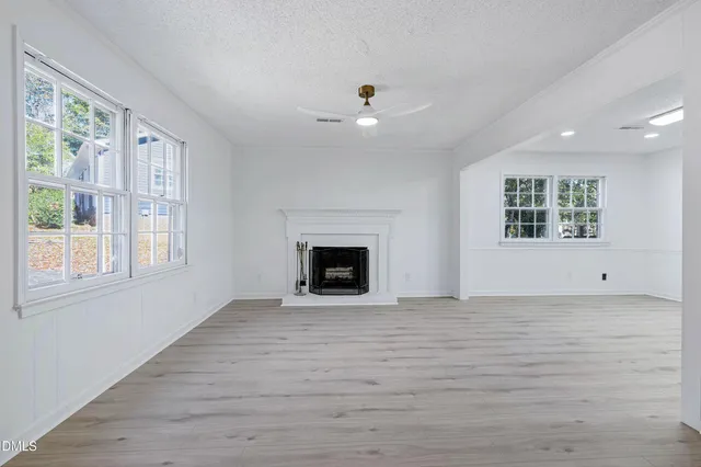 a view of an empty room with a window and fireplace