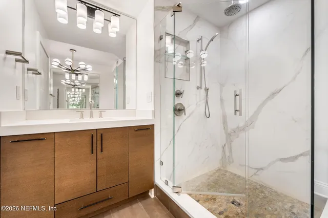 a bathroom with a granite countertop sink a mirror and shower