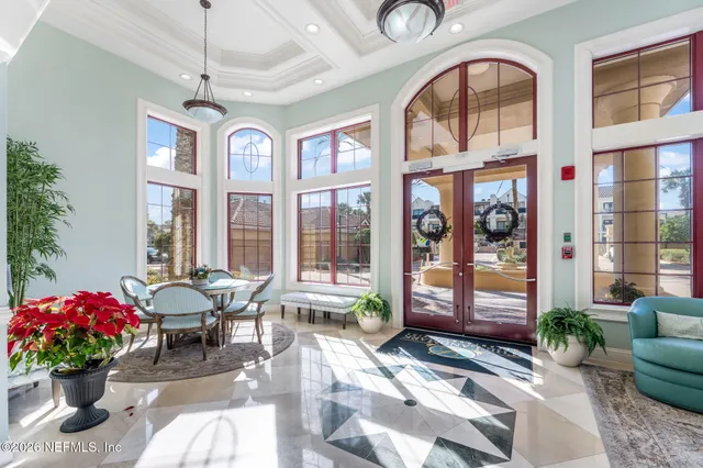 a living room with patio furniture and floor to ceiling windows
