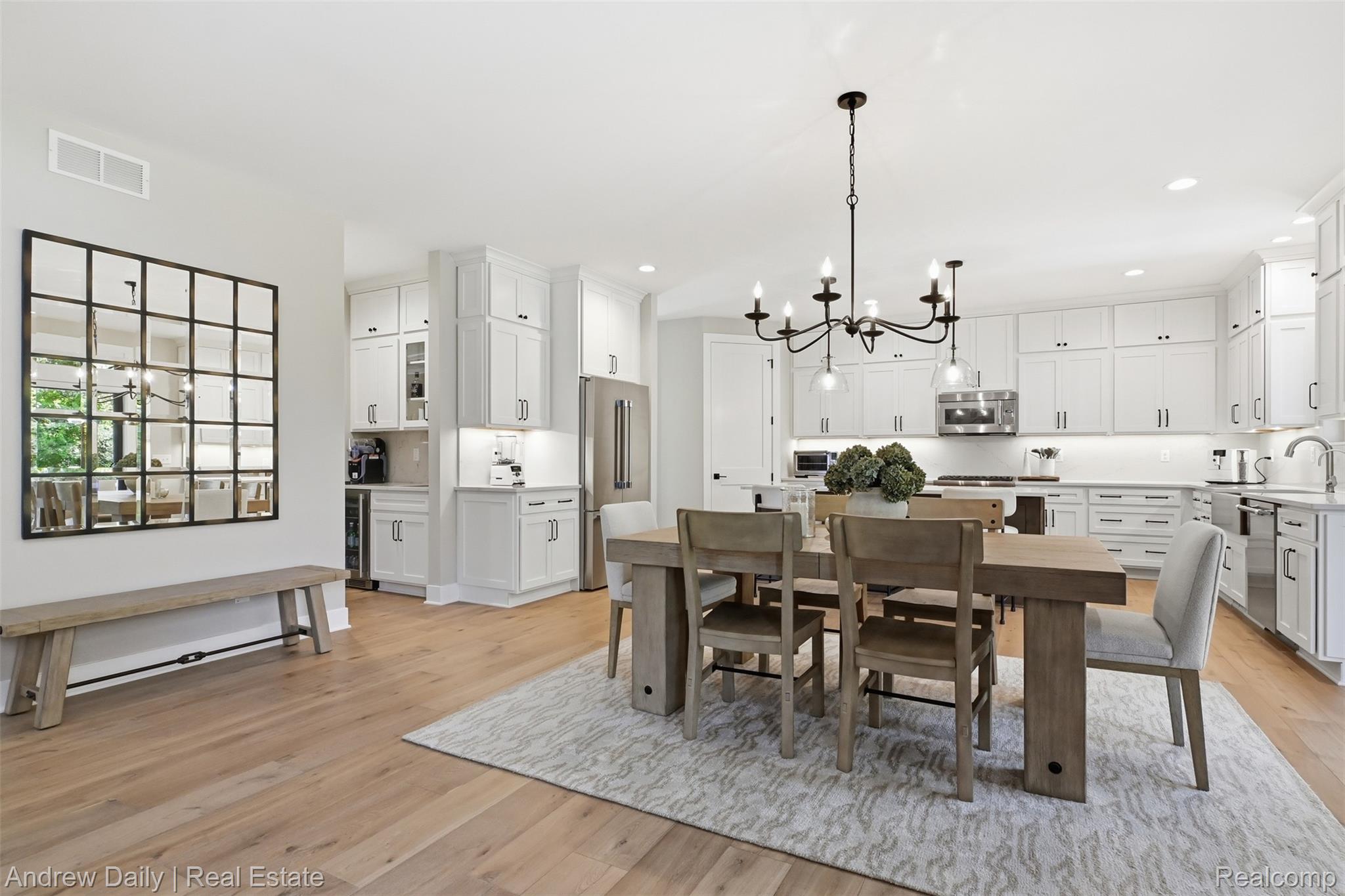 4661 Spears Road Pinckney, MI 48169 - Photo 18 of 56 Spacious kitchen and dining area featuring light wood-finish flooring, white cabinetry with dark hardware, stainless steel appliances, and an elegant chandelier