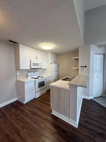 a kitchen with stainless steel appliances a white cabinets and wooden floor