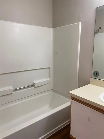 a kitchen with stainless steel appliances a refrigerator a stove a sink and white cabinets with wooden floor