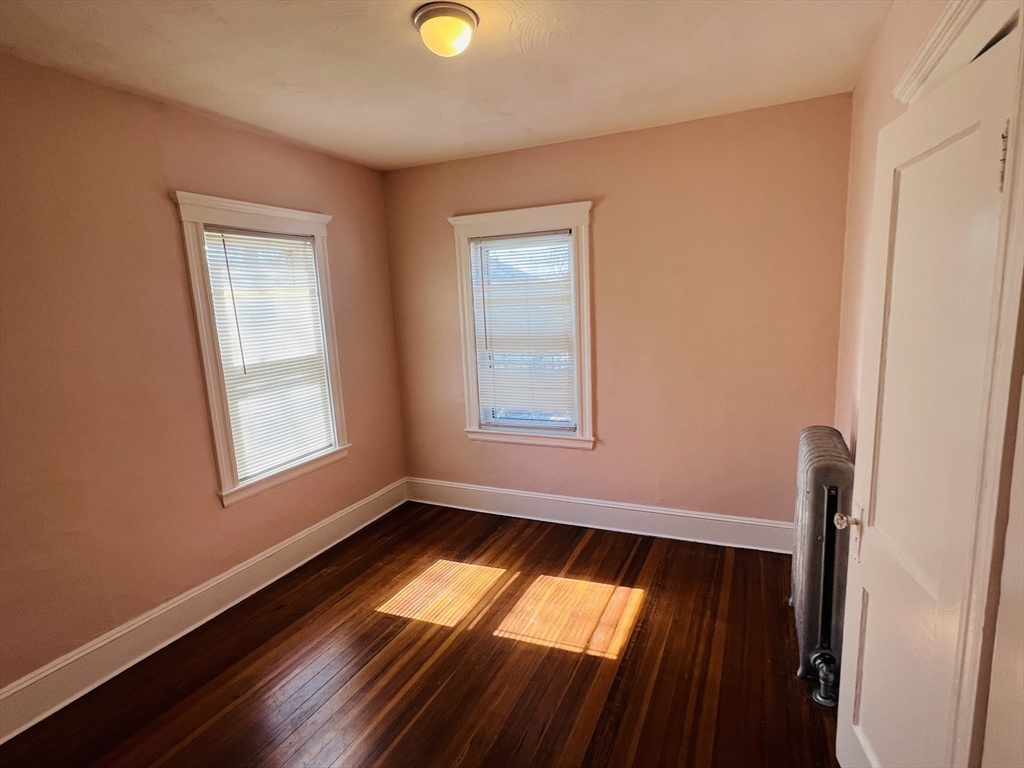62 Westmore Road, Unit 2 Boston, MA 02126 - Photo 9 of 13 a view of an empty room with wooden floor and a window