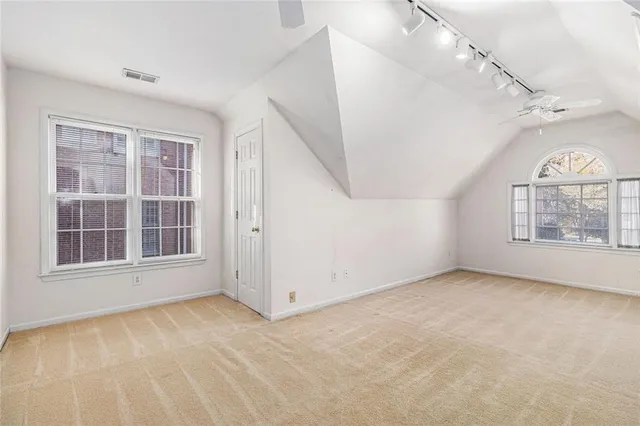 an empty room with chandelier fan and windows