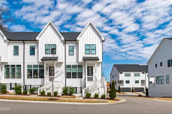 a view of a white house with large windows and a small yard