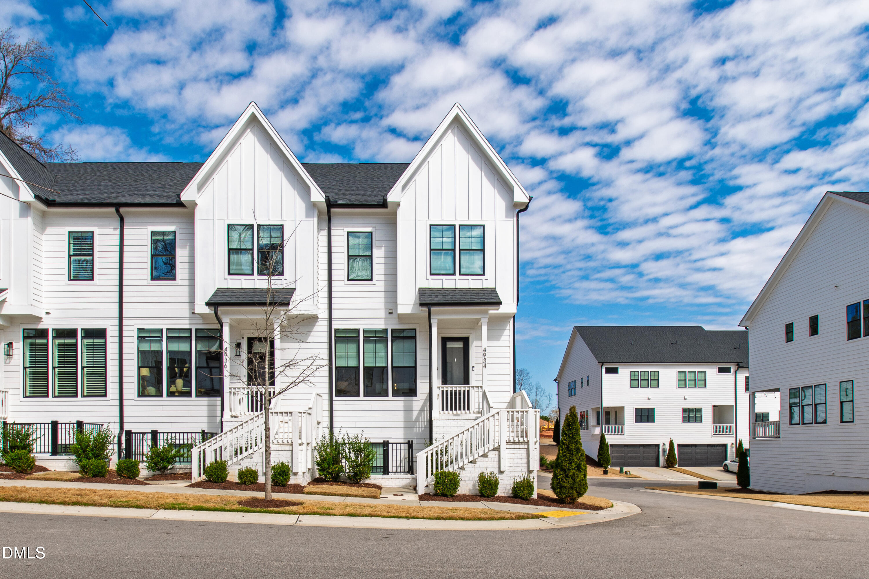 a view of a white house with large windows and a small yard
