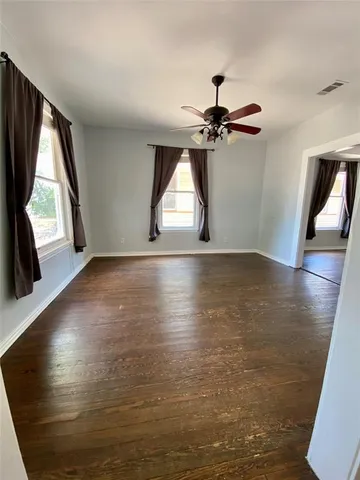 a view of empty room with wooden floor and fan