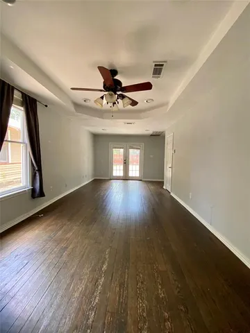 a view of empty room with wooden floor and fan