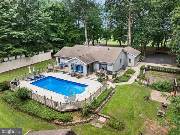 an aerial view of a house with swimming pool and large trees