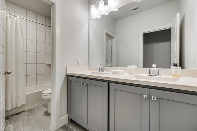 a bathroom with a double vanity sink toilet and shower