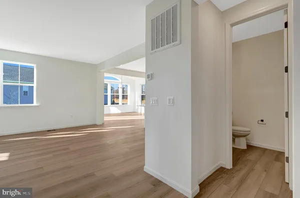 a view of empty room with wooden floor and kitchen