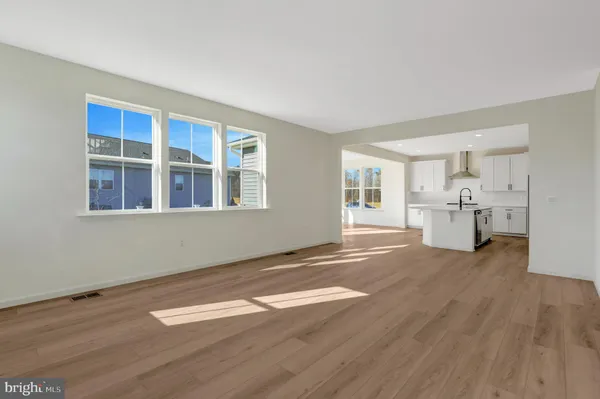 a large kitchen with stainless steel appliances kitchen island a stove a refrigerator a sink dishwasher a oven and white cabinets with wooden floor