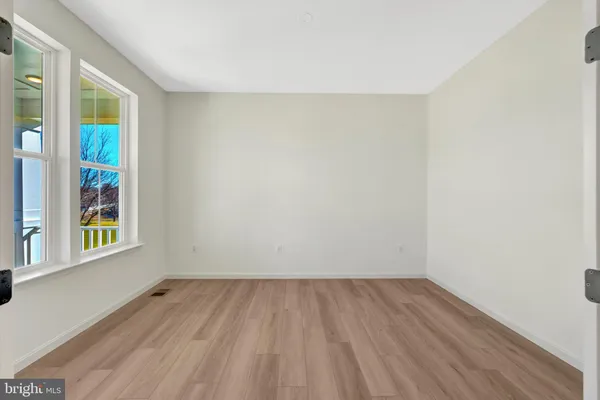 a view of a hallway with wooden floor and a bathroom