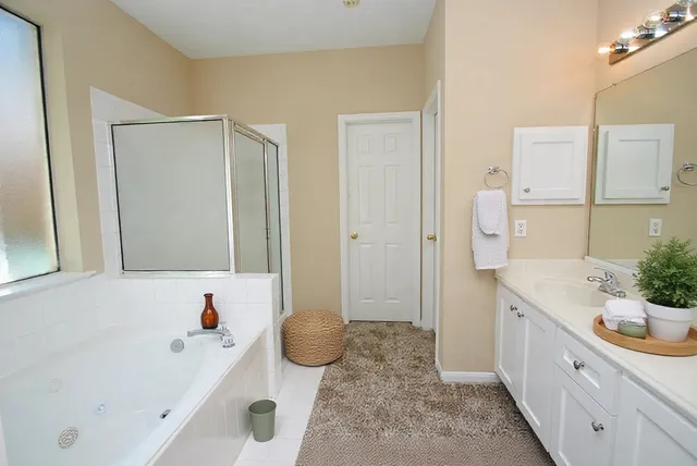 a spacious bathroom with a tub sink and mirror