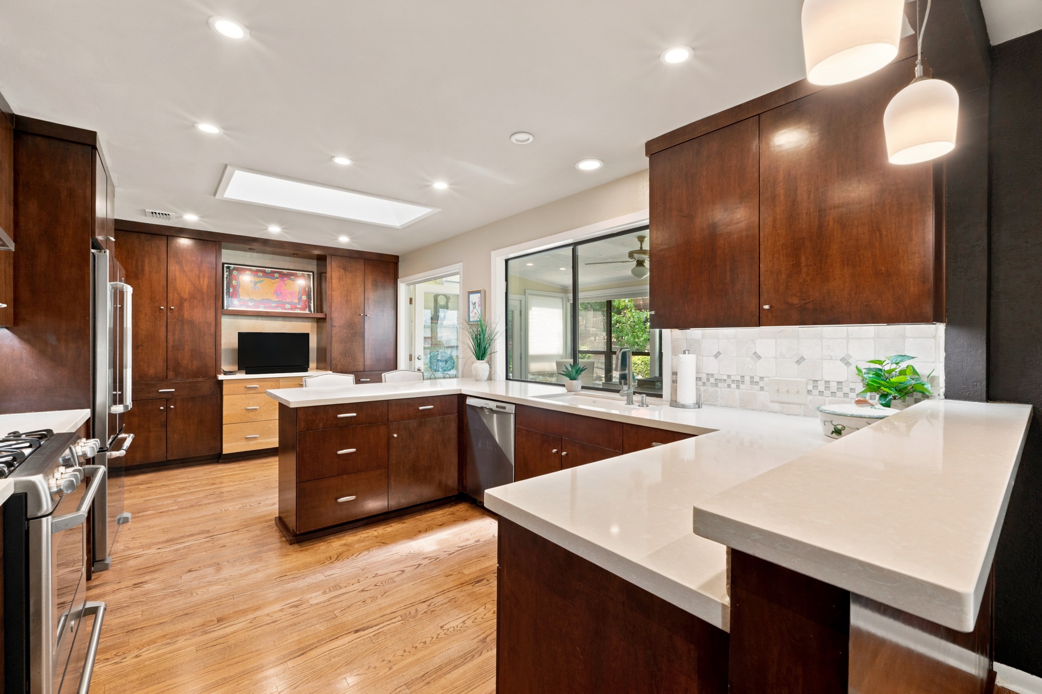 1904 Stoneridge Road Austin, TX 78746 - Photo 14 of 40 Quartz countertops and warm wood cabinetry create a polished, functional kitchen workspace.