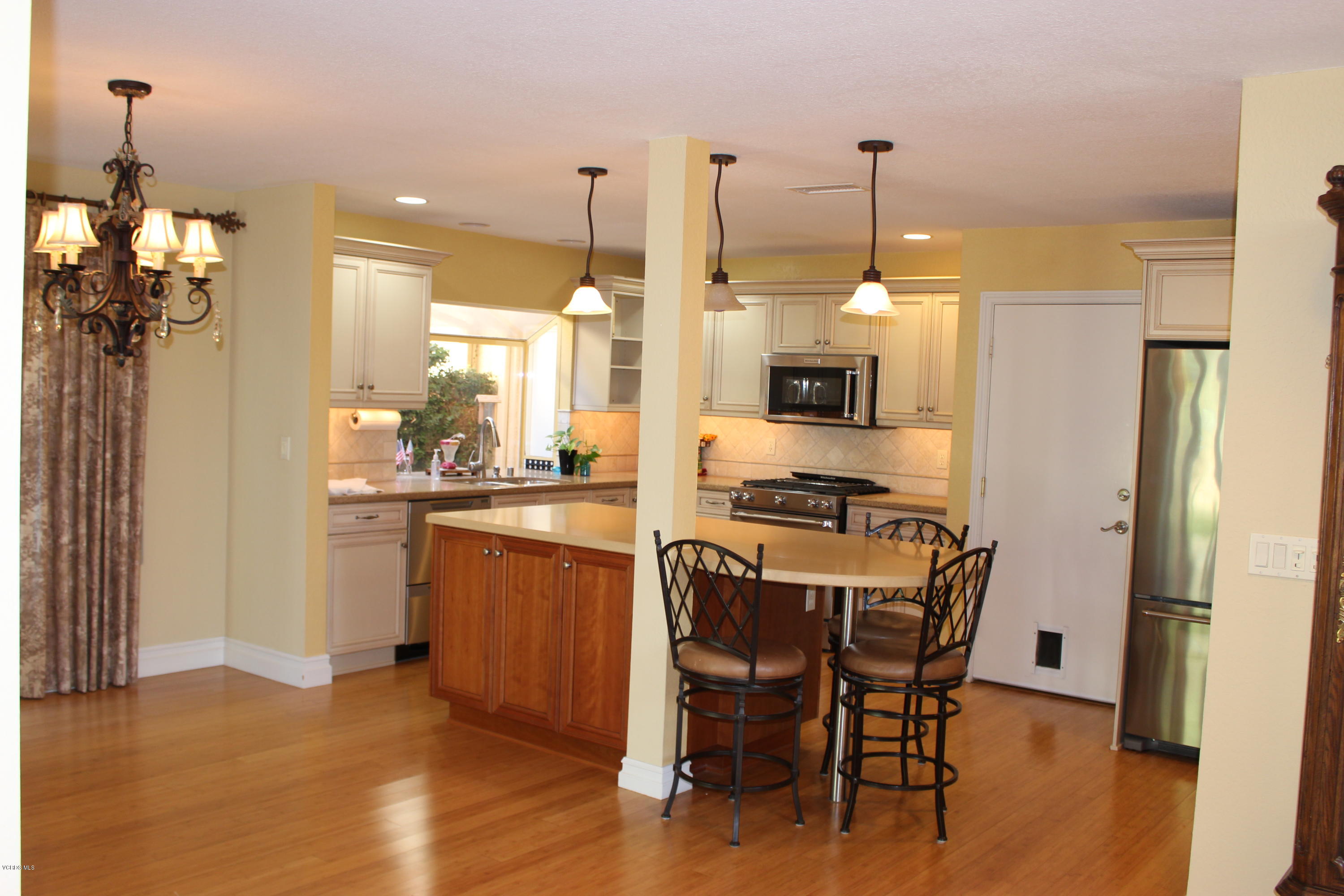 605 Galloping Hill Road Simi Valley, CA 93065 - Photo 6 of 35 a kitchen with a table chairs refrigerator and microwave