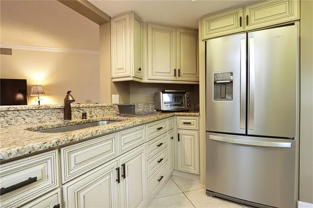 a kitchen with stainless steel appliances granite countertop a refrigerator a sink and white cabinets