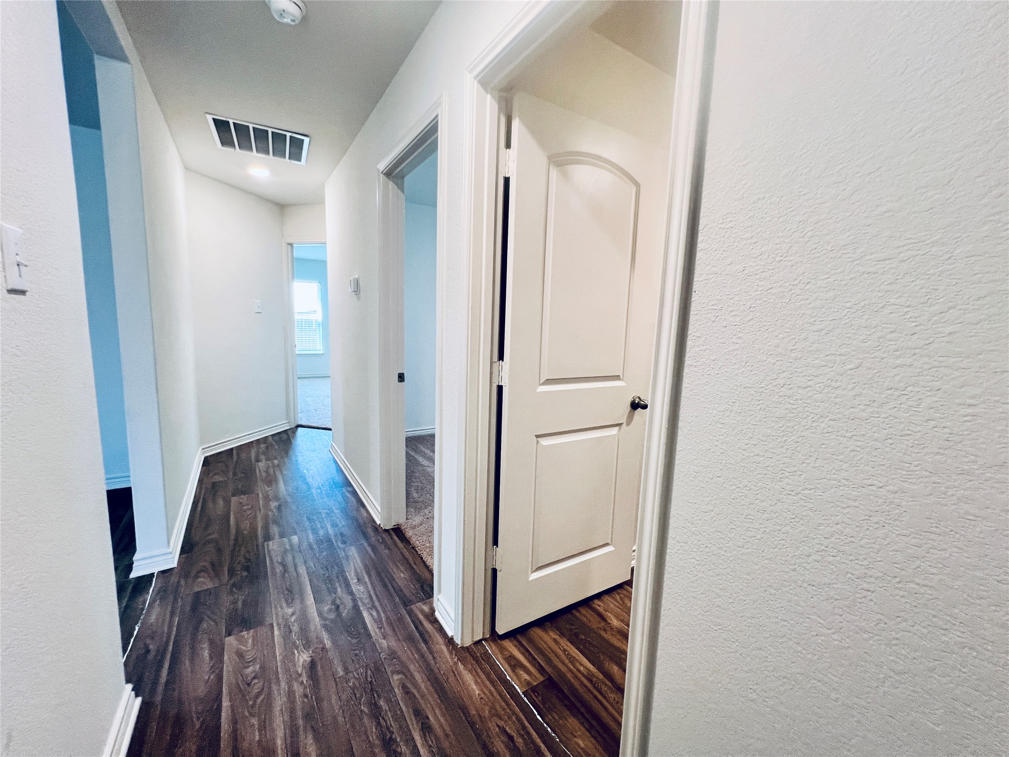 520 Locksley Cove Jarrell, TX 76537 - Photo 9 of 27 A well-lit corridor with rich wood-look flooring leads to inviting interior spaces.