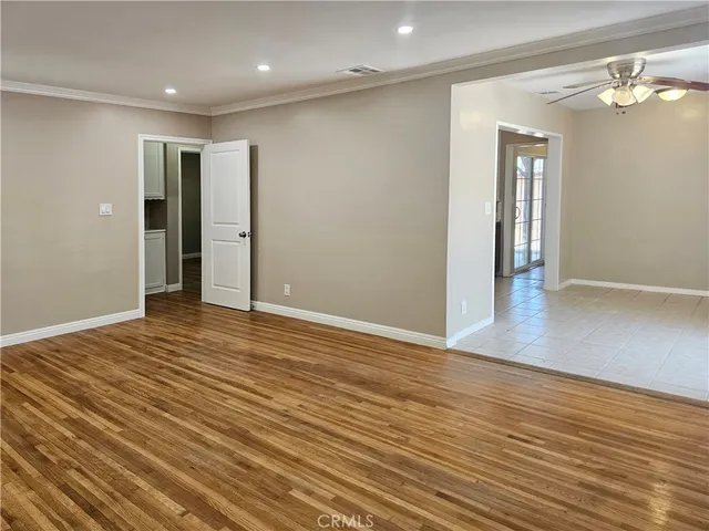 a view of an empty room with wooden floor and a bathroom