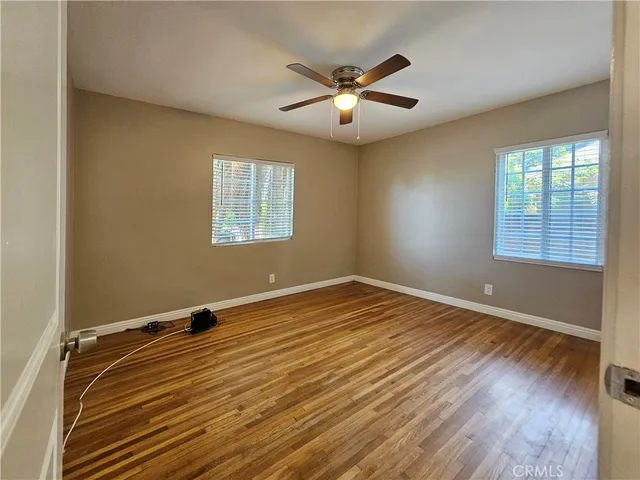 a view of an empty room with window and wooden floor