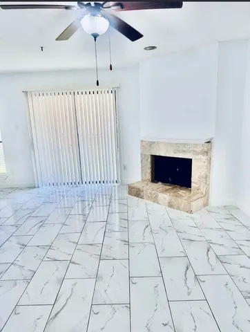 a living room with a fireplace furniture a ceiling fan and a rug