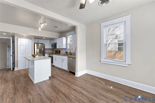 a kitchen with white cabinets and wooden floor
