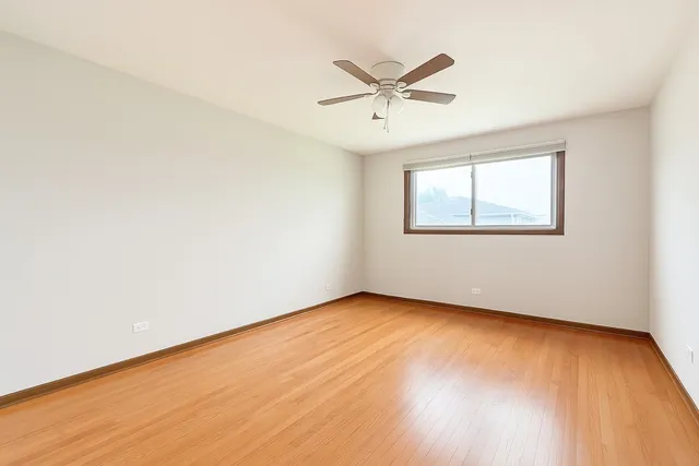 an empty room with wooden floor fan and windows